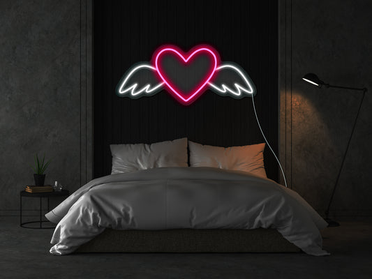 A pink neon sign of a heart with wings, illuminating a dimly lit room, perfect for romantic or love-themed decoration