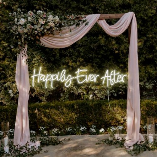 A neon 'Happily Ever After' sign against a backdrop of a wedding arch, signaling a joyful union