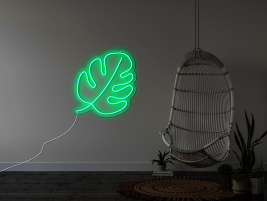 "A bright neon sign of a monstera leaf, with the leaves in green and the veins in yellow, illuminating a dimly lit room, perfect for a plant lover or tropical-themed decoration